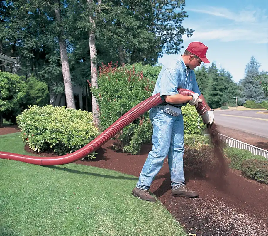 man blowing applying mulch through big pipe